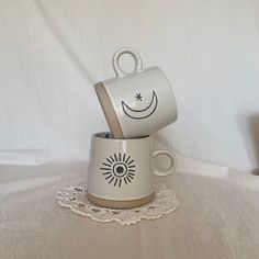 two coffee mugs sitting on top of each other with faces drawn on the cups