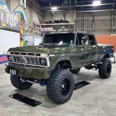 a large green truck parked inside of a building