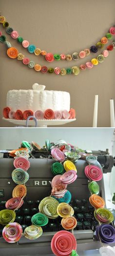 paper flowers are hanging on the wall next to an old typewriter and a cake