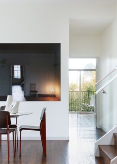 a dining room table and chairs in front of a painting on the wall with stairs leading up to it