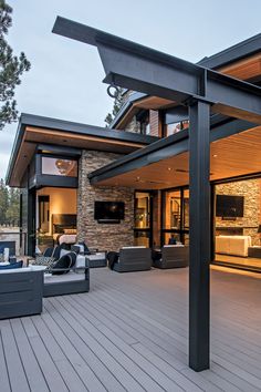 an outdoor living area with couches, tables and television on top of a wooden deck