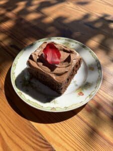 a piece of chocolate cake on a plate with a strawberry in the middle, sitting on a wooden table