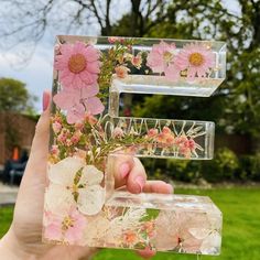 a person holding up a clear case with pink flowers on it and the letter e