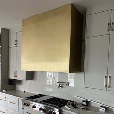 a stove top oven sitting inside of a kitchen next to white cupboards and drawers