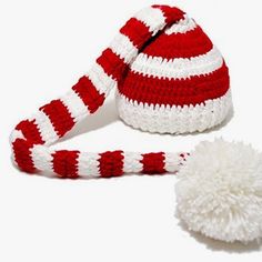 a red and white knitted hat next to a white pom - pom