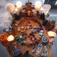 a wooden table topped with lots of different types of stones and candles on top of it