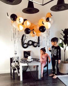 two children standing in front of a table with balloons