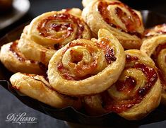 some very tasty looking pastries on a black plate with red sauce in the middle