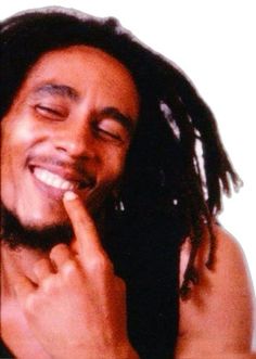 a man with dreadlocks smiling and holding his finger to his mouth