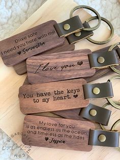 four wooden keychains with engraved words on them, one saying i love you