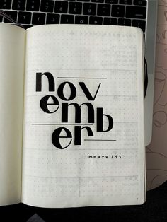 an open notebook with the words november written in black on it next to a keyboard