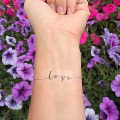 a woman's wrist with the word love written in cursive writing on it