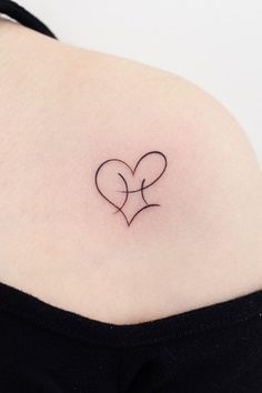 a small tattoo on the back of a woman's shoulder that has two hearts in it