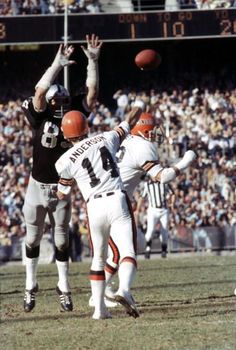 two football players are jumping up to catch the ball in front of an opposing team