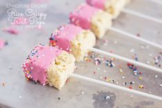 cake pops with pink frosting and sprinkles are on a baking sheet