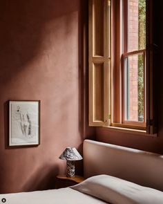 a bed sitting under a window next to a lamp