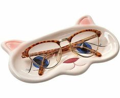 a pair of glasses sitting on top of a cat shaped plate with blue eyes and ears