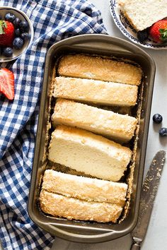 a pan filled with sliced cake next to berries