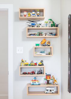 three wooden shelves with toy cars and trucks on them in the corner of a room