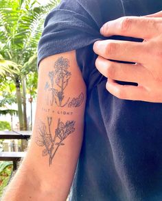 a man with a tattoo on his arm holding onto another person's arm that has flowers and words tattooed on it