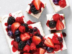 four desserts with berries and cream on them are arranged in the shape of squares