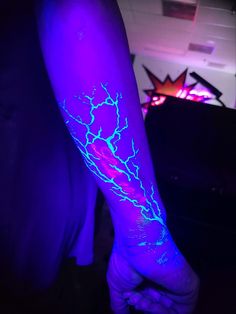 a person's arm with blue and purple lightening on it, in the dark