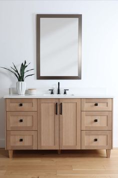 a bathroom vanity with two sinks and a large mirror above it, in front of a white wall