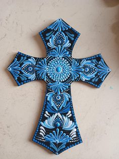 a blue and white painted cross sitting on top of a table