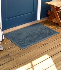 a blue front door with a welcome mat on the wooden floor in front of it