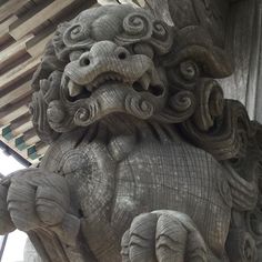 an intricately carved stone lion on the side of a building with wood slats