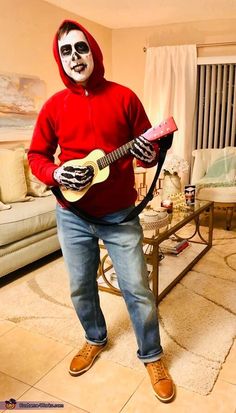 a man in a red hoodie is holding a guitar and wearing a skeleton mask