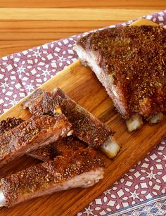 two pieces of meat sitting on top of a wooden cutting board