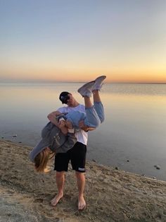 a man holding onto another person on the beach