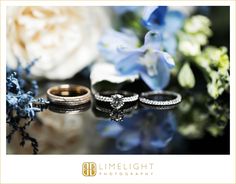 two wedding rings sitting on top of a table next to blue flowers and white orchids