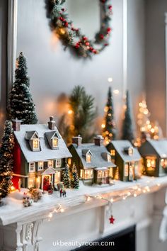 a fireplace mantel decorated with christmas lights and miniature houses