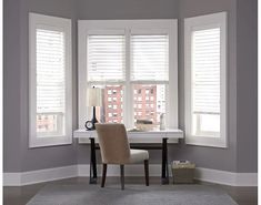 a chair sitting in front of two windows with shutters on each side and a rug on the floor