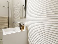 a white sink sitting under a bathroom mirror next to a wall mounted faucet