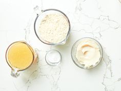 three different types of food in glass bowls on a marble counter top, with one being whipped cream and the other is sour cream