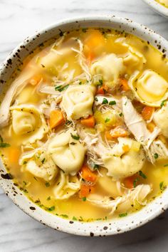 two bowls of soup with dumplings and carrots