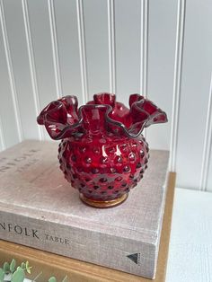 a red vase sitting on top of a book