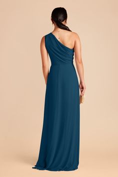 a woman in a long blue dress with one shoulder draped over her shoulders, looking back