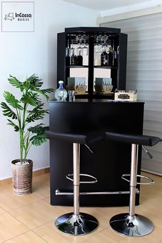 two black barstools sitting in front of a cabinet with wine glasses on it