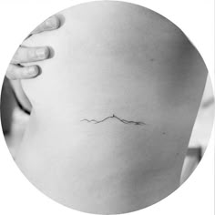 a woman's stomach with a small mountain tattoo on it