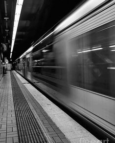 black and white photograph of a subway train passing through the station with it's lights on