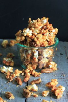 a glass bowl filled with popcorn sitting on top of a wooden table