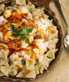 a bowl filled with pasta and sauce on top of a table next to a spoon