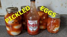 several jars filled with pickled eggs sitting on a counter top next to each other