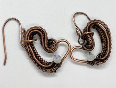 These earrings have layers of wire wrapped copper that form an asymetrical heart with a Rainbow Moonstone accent.Hang from handmade copper ear wires.Approximately 1 5/8" long from the top of the ear wire and just over 1" wide.Based on a Nicole Hanna Design.These earrings have been antiqued, polished and sealed.Sealed with Protectaclear ProtectaClear is a clear, protective coating that is tough enough to protect jewelry and is safe for wear against skin. ProtectaClear is practically invisible onc Hanna Design, Earthy Aesthetic, Copper Heart, Handcrafted Accessories, Handmade Copper, A Rainbow, Ear Wire, Heart Earrings, Rainbow Moonstone