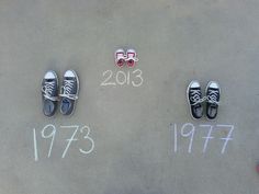 three pairs of shoes sitting on top of a cement floor next to numbers written in chalk