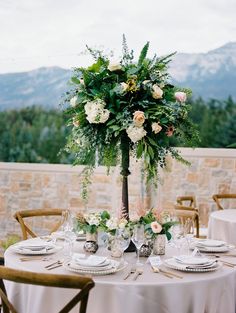 a table set up with flowers and greenery for a wedding reception in the mountains